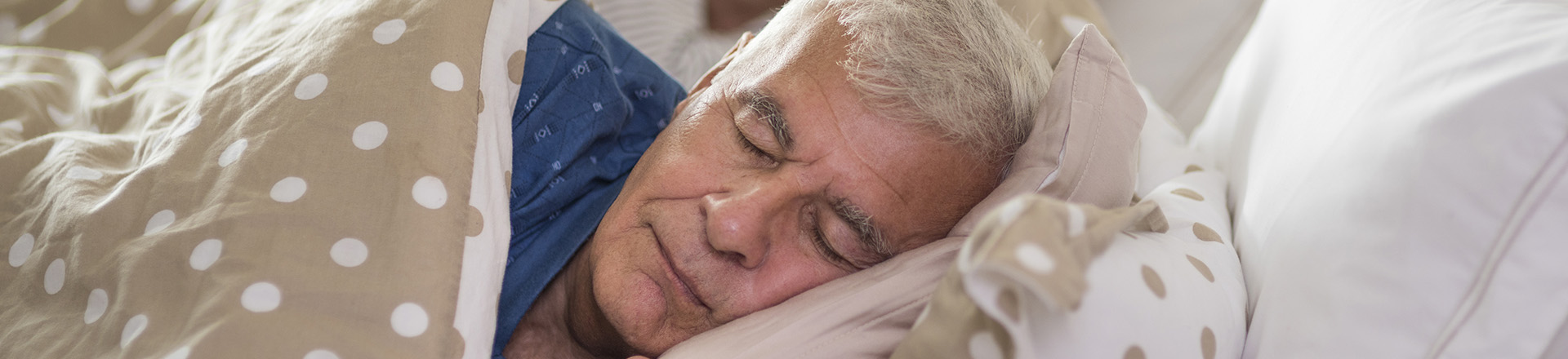 Un vieil homme dort dans un lit