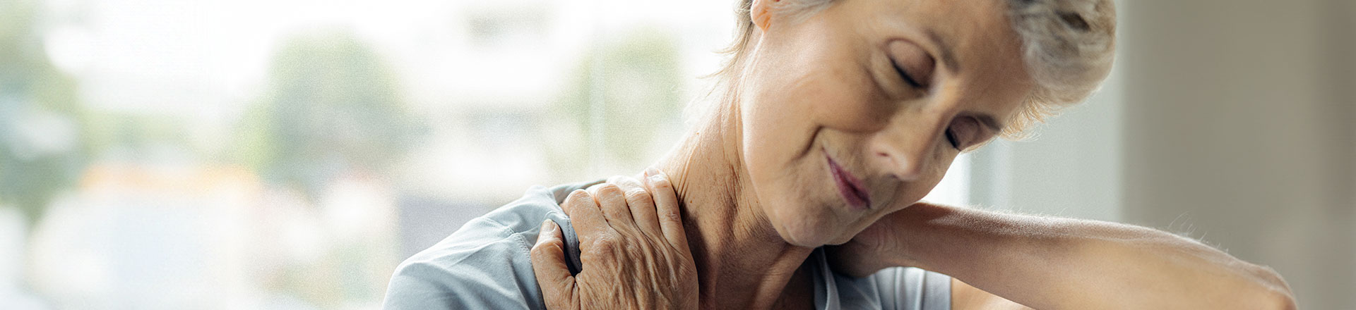 Une femme se tient le cou pour soulager sa douleur